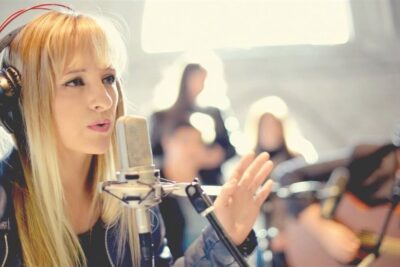Cantante femenina en estudio con micrófono y auriculares, ambiente íntimo ideal para temas de espiritu santo