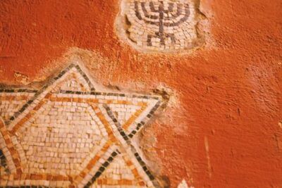 Mosaico en muro envejecido mostrando una estrella de David y una menorá, estrella david significado simbolismo revelados.
