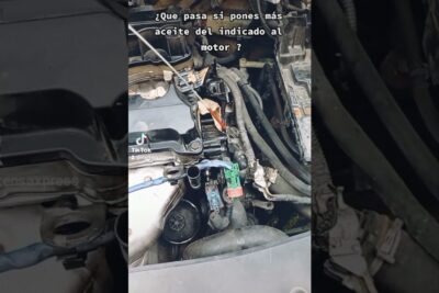 Dipstick y compartimento del motor con tapa abierta mostrando riesgo por exceso aceite