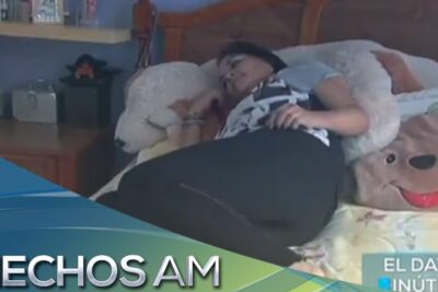 Mujer recostada en cama rodeada de peluches que ilustra falta sueno 1