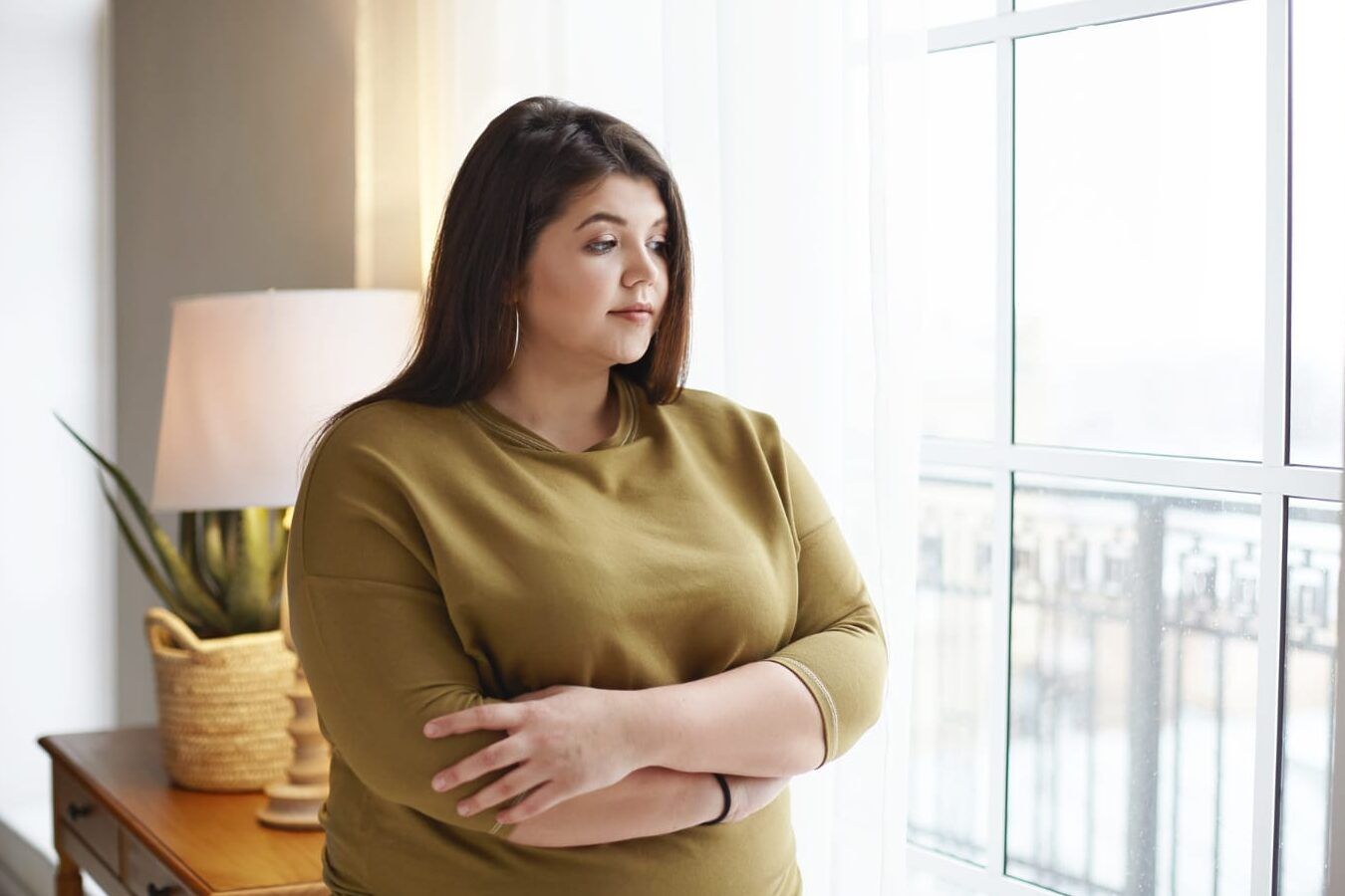 Mujer pensativa junto a la ventana, reflexionando sobre fumar antes de una gastroscopia descubre aqui lo que puede suceder