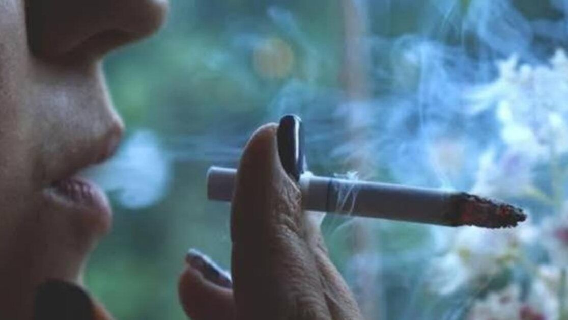 Primer plano de labios y mano sosteniendo un cigarrillo encendido con humo, fumar un cigarrillo al mes es beneficioso para la salud descubre la verdad aqui