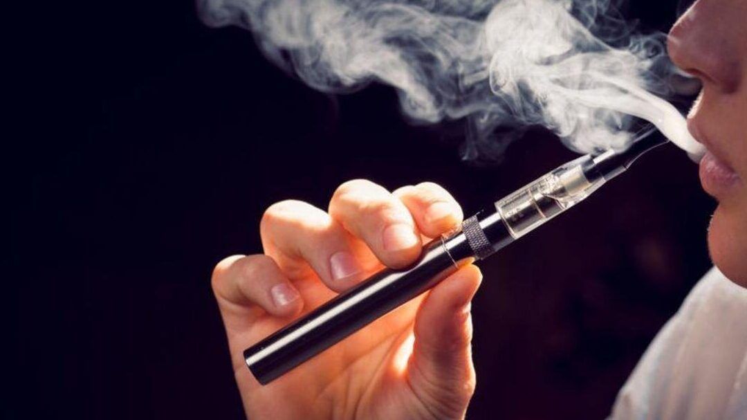 Persona exhalando vapor de un cigarrillo electrónico, fumar vaper y tabaco juntos descubre las consecuencias.