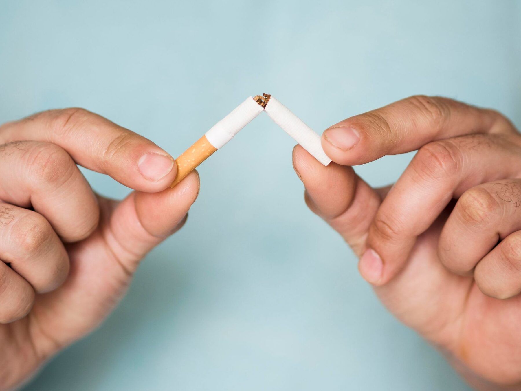 Manos rompiendo un cigarrillo en señal de dejar de fumar, fumas y te van a sacar sangre descubre lo que sucede en tu cuerpo