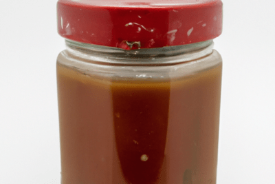 Tarro sellado de vidrio con líquido rojo y tapa metálica roja, gazpacho caducado sin abrir es seguro consumirlo