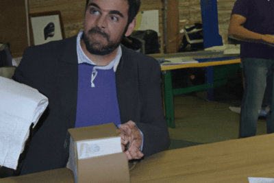 Persona revisando una caja y documentos sobre una mesa en un espacio de trabajo mientras comprueba si ha caducado o caducado todo lo que necesitas saber sobre la caducidad de productos y documentos.