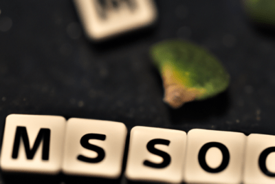 Fichas de letras en primer plano junto a hojas verdes sobre fondo oscuro, evocando hipromelosa caducada que debes saber y como afecta tu salud