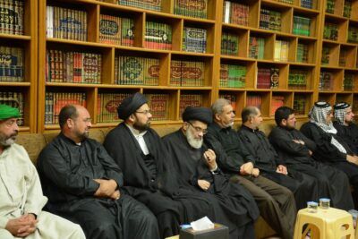 Grupo de hombres con vestimenta tradicional sentados frente a estanterías llenas de libros, interpretación sonar atrapado habitacion cerrada