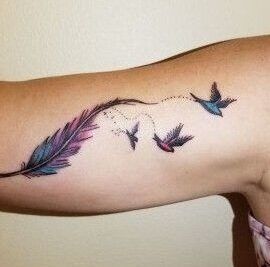 Tatuaje de pluma acuarela en el antebrazo que se transforma en tres aves en vuelo, interpretacion y simbolismo de un tatuaje de pluma de pajaro.