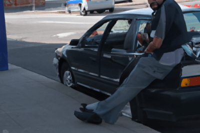 Hombre apoyado en la puerta de su coche en la ciudad itv caducada que hacer y cuanto cuesta la multa
