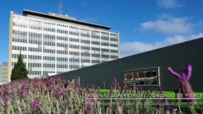 Fachada moderna de un edificio judicial con jardineras floridas, referencia para juzgado encontrar.