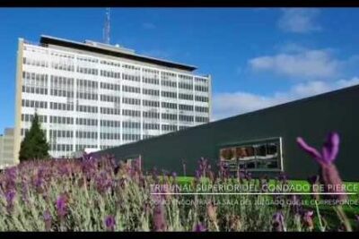 Fachada moderna de un edificio judicial con jardineras floridas, referencia para juzgado encontrar.