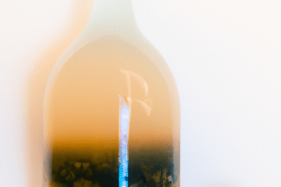 Botella con líquido ámbar turbio y una masa gelatinosa en suspensión que acompaña la búsqueda kombucha caducada es seguro beberla