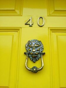 Puerta amarilla con el número 40 y una aldaba de león de metal, la interpretacion del numero y su significado guia completa.