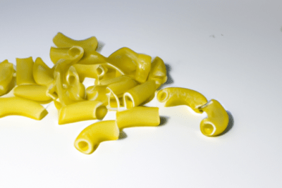 Trozos de pasta seca sobre fondo blanco que ilustran la consulta la pasta caducada se puede comer
