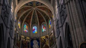 Interior de catedral con bóveda decorada, vitrales coloridos y frescos en el ábside que evocan logros destacados almudena cid gimnasia ritmica
