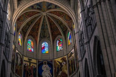 Interior de catedral con bóveda decorada, vitrales coloridos y frescos en el ábside que evocan logros destacados almudena cid gimnasia ritmica