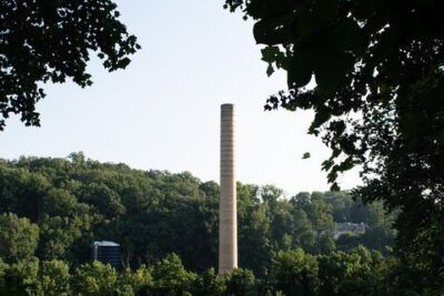 Chimenea industrial alta entre copas de árboles en un paisaje boscoso, lugares turisticos aranda duero