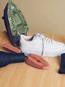 Air Force 1 blancos sobre mesa con plancha, secador, hormas de madera y paño listos para limpieza; manten tus air force 1 impecables zapatillas frescas y limpias.