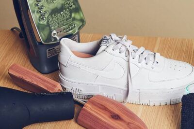 Air Force 1 blancos sobre mesa con plancha, secador, hormas de madera y paño listos para limpieza; manten tus air force 1 impecables zapatillas frescas y limpias.