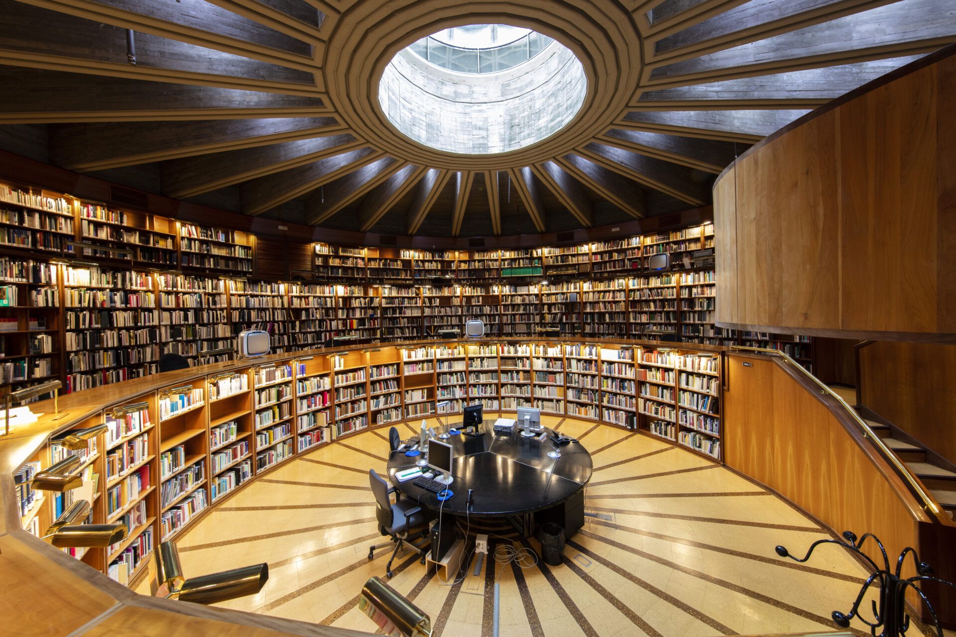 Sala de biblioteca circular con escritorio central y estanterías para mostrar interes por los libros.
