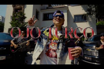 Cartel de video urbano ojo turco con cantante en primer plano, banda y coches de fondo