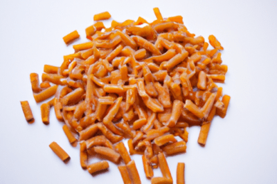 Montón de pasta corta con salsa naranja y textura brillante, pasta caducada es seguro consumirla despues de la fecha de vencimiento