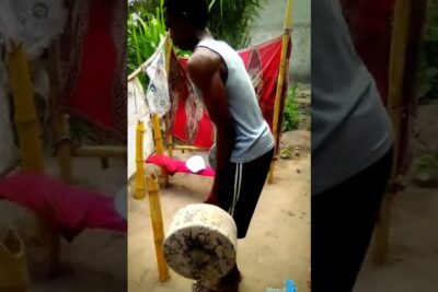 Persona levantando un objeto cilíndrico de concreto que representa un peso elevado durante un entrenamiento al aire libre.