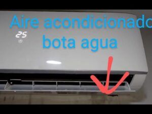 Unidad interior de aire acondicionado montada en pared con agua goteando por la parte inferior y flecha roja indicando el punto por que mi aire acondicionado gotea agua descubre como solucionarlo