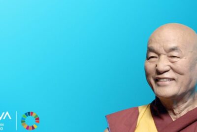 Monje budista sonriente con túnica roja y amarilla sobre fondo azul que comen los budistas guia completa sobre la alimentacion en la practica budista