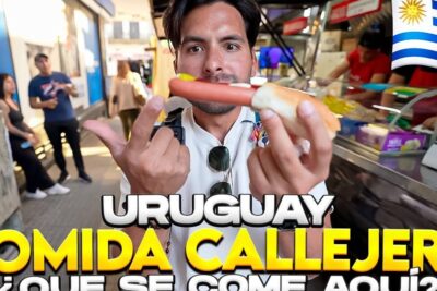 Persona mostrando un pan con salchicha y mostaza en un puesto de calle en Uruguay que comen los uruguayos platos tradicionales de uruguay y sus secretos culinarios
