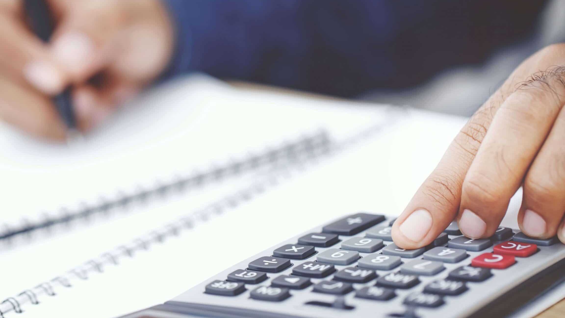 Mano usando calculadora y cuaderno para revisar cifras sobre que consecuencias hay si haces mal la declaracion de la renta en espana