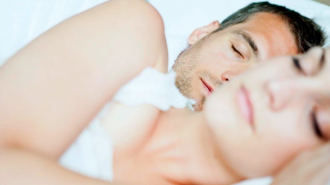 Pareja dormida en la cama, imagen para ilustrar que consecuencias tiene dormir junto al celular descubre los riesgos en temas de sueño y salud