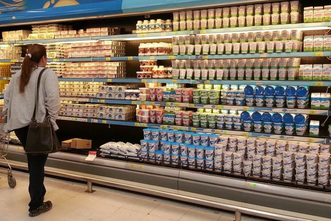 Cliente mirando una góndola refrigerada con envases de queso cremoso y preguntándose que consecuencias tiene el queso cremoso sin cadena de frio