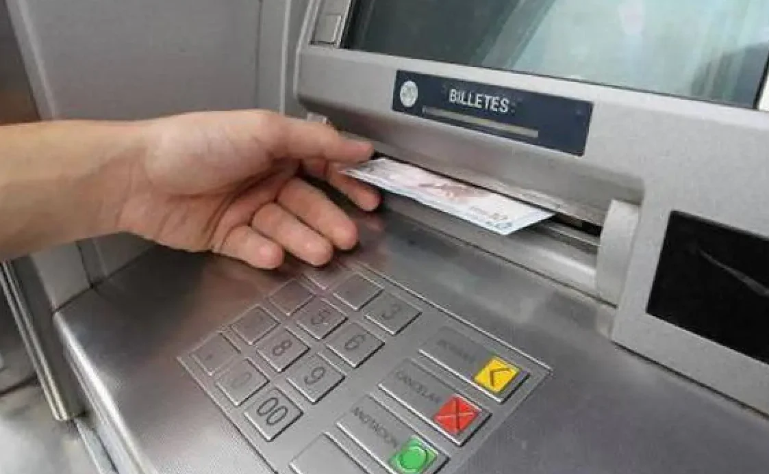 Mano sacando un billete de un cajero automático, que consecuencias tiene ingresar grandes cantidades de dinero en una cuenta online