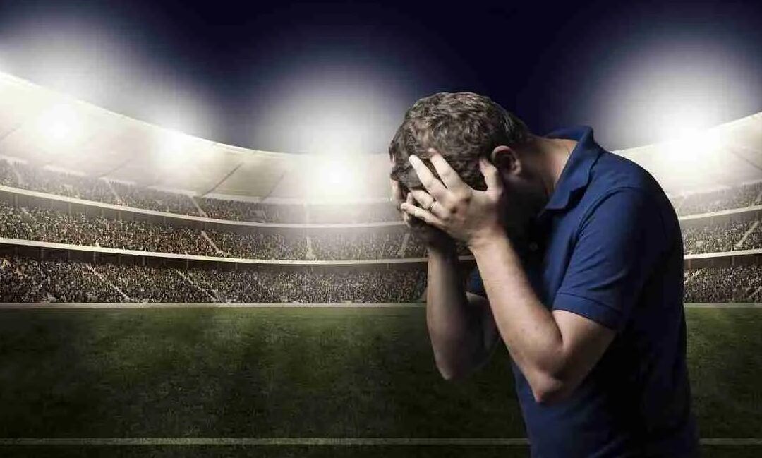 Hombre en estadio sujetándose la cabeza que evoca que efectos tiene jugar futbol diariamente en tu cuerpo.