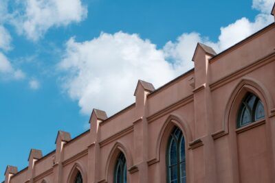 Fachada rosada con arcos ojivales y detalles arquitectónicos bajo un cielo azul brillante, que es el aove descubre la quinta esencia del aceite de oliva