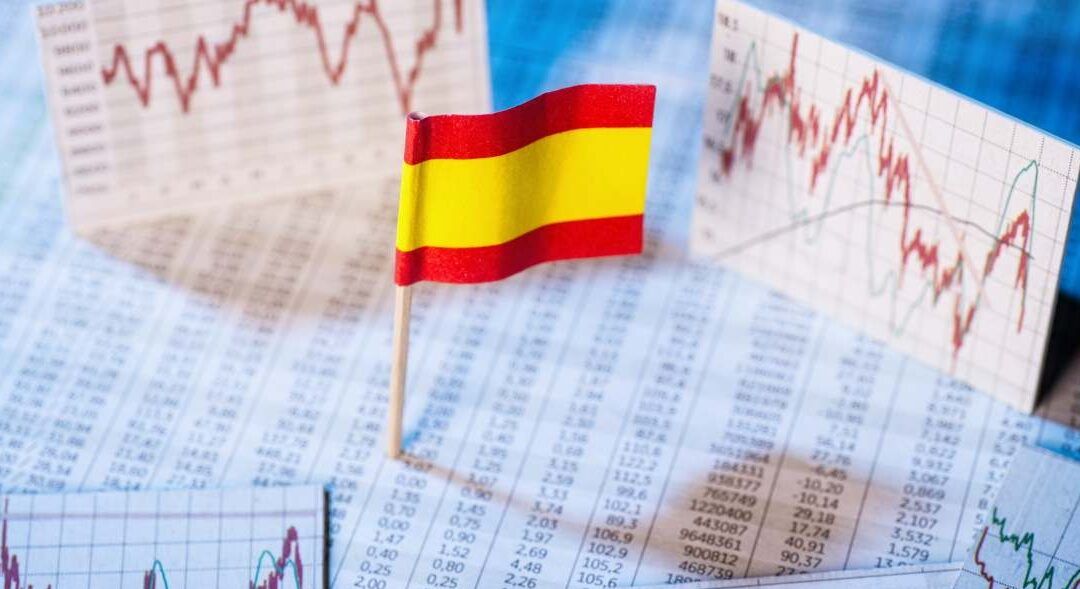 Mini bandera de España sobre tablas y gráficos financieros que es el limite de renta per capita familiar y como afecta tus impuestos 1