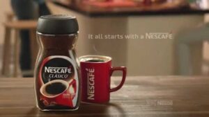 Frasco de Nescafé Clásico junto a una taza roja humeante sobre una mesa de madera, que es el marketing emocional ejemplos