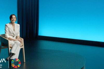 Mujer vestida de blanco sentada en un escenario minimalista explicando que es la neurociencia aplicada