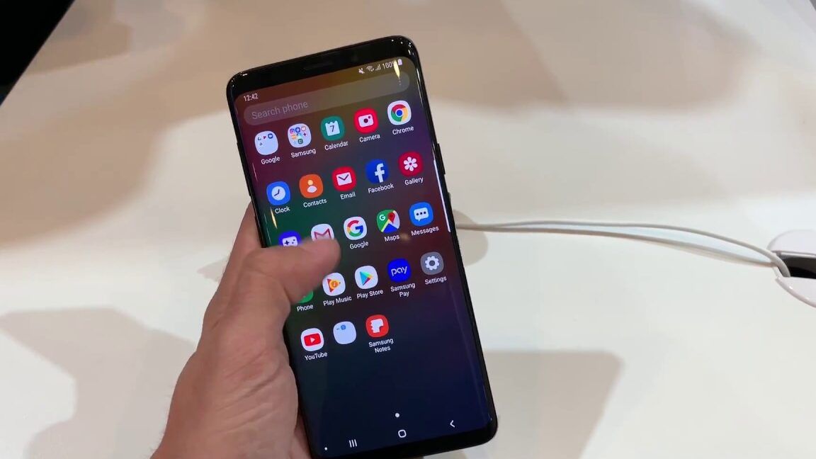 Mano sosteniendo un móvil Samsung con el lanzador de aplicaciones y ajustes visibles que es one ui en mi celular descubre todo sobre esta interfaz innovadora.