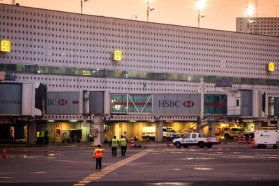 Personal de pista junto a pasarelas de embarque y vehículos de servicio en un aeropuerto al atardecer, que hacer aranda duero vacaciones inolvidables