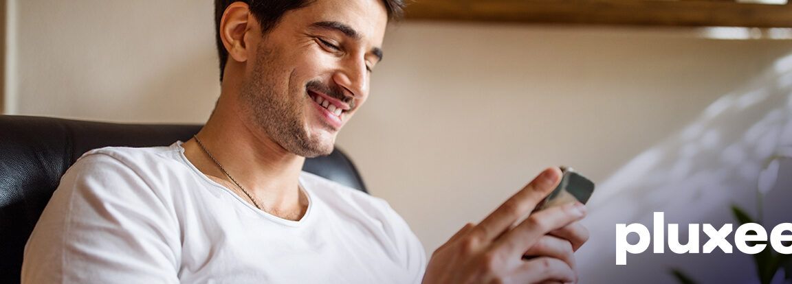 Hombre sonriente consultando su móvil que hacer si uber eats tarda en llegar aprende aqui