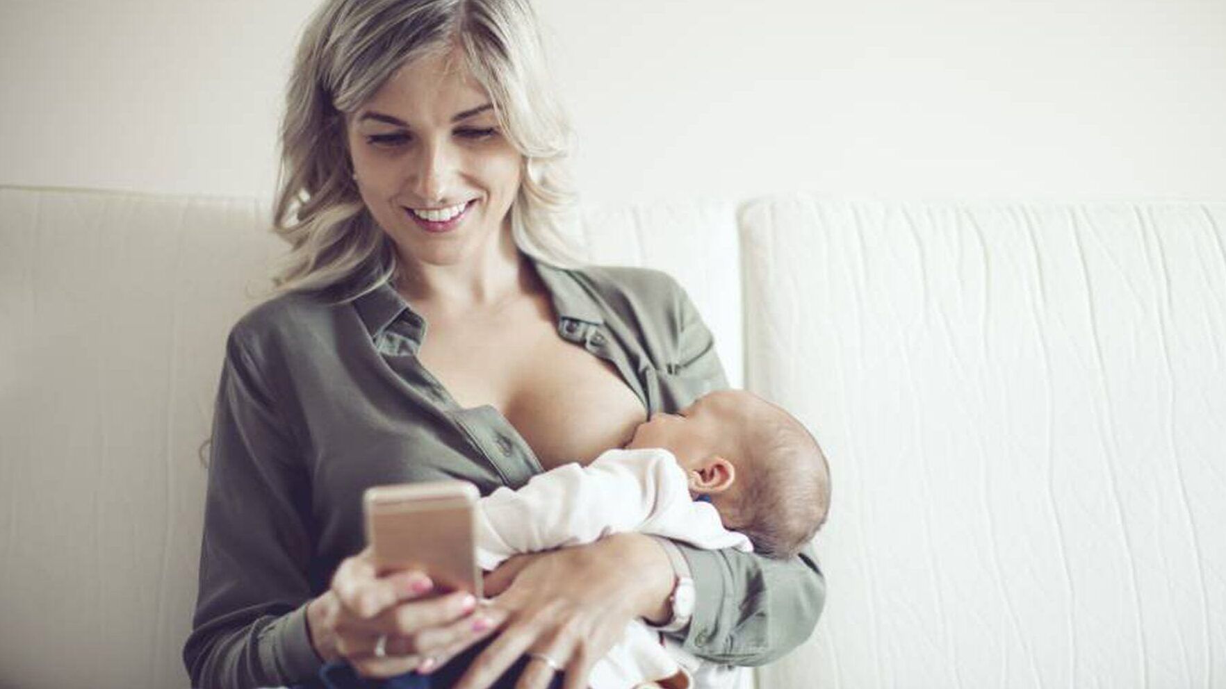 Mujer amamantando a su bebé mientras mira el móvil que pasa si cambio la leche de mi bebe descubre las consecuencias aqui 1