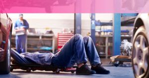 Mecánico acostado bajo un coche en un taller realizando una inspección y reparación — que pasa si el seguro del coche no esta a mi nombre descubre las consecuencias 1