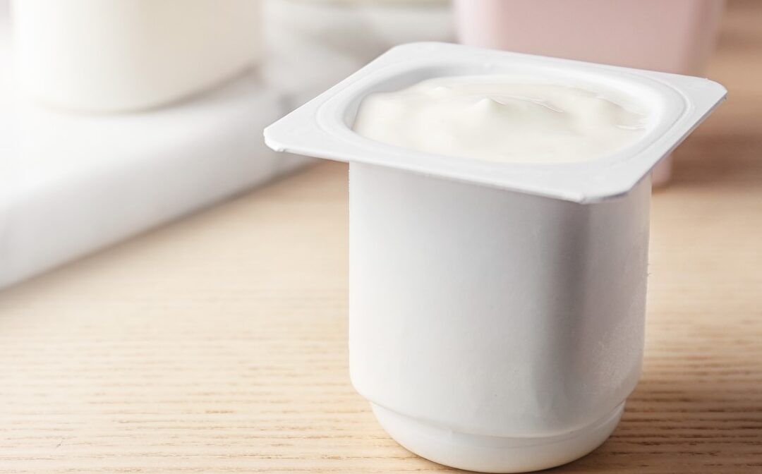Yogur natural en envase plástico abierto con textura cremosa que pasa si el yogur esta acido descubre sus efectos en tu salud.