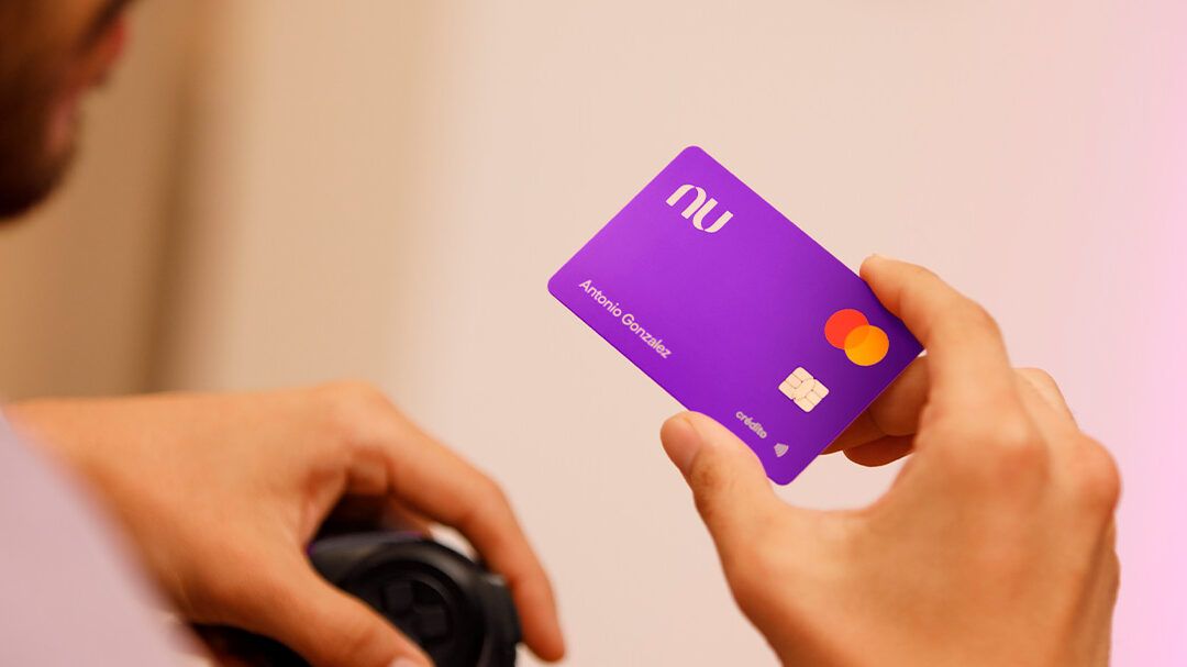 Manos sosteniendo una tarjeta púrpura con chip que plantea que pasa si ingreso mucho dinero en mi cuenta google descubre las consecuencias aqui