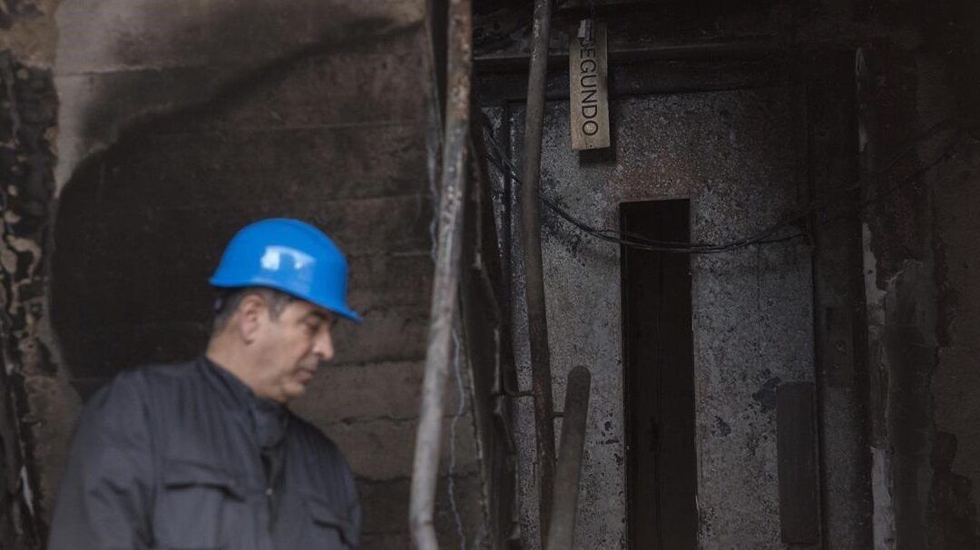 Trabajador con casco azul inspecciona un interior oscuro y deteriorado mientras se consideran que pasa si le cortas la luz a un okupa consecuencias y posibles soluciones.