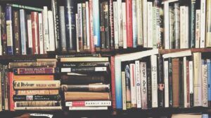 Estantería con libros apilados de distintos tamaños y colores que representa el emoji libro significado interpretacion.