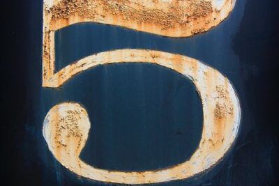 Placa metálica envejecida con el número 5 visible, que representa el numero descubre su significado y simbolismo